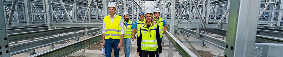 Gruppe von voestalpine Mitarbeiter:innen besichten die Hochregal-Anlage
