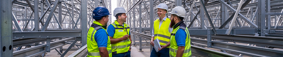 Gruppe von Mitarbeiter:innen besprechen sich im Hochregal Lager